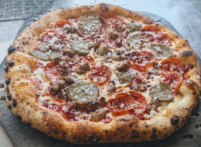 A pepperoni and sausage pizza lifted on the peel