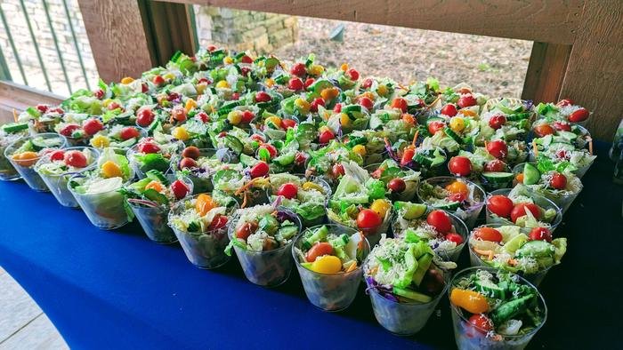 Rows of salad cups laid out on a catering table