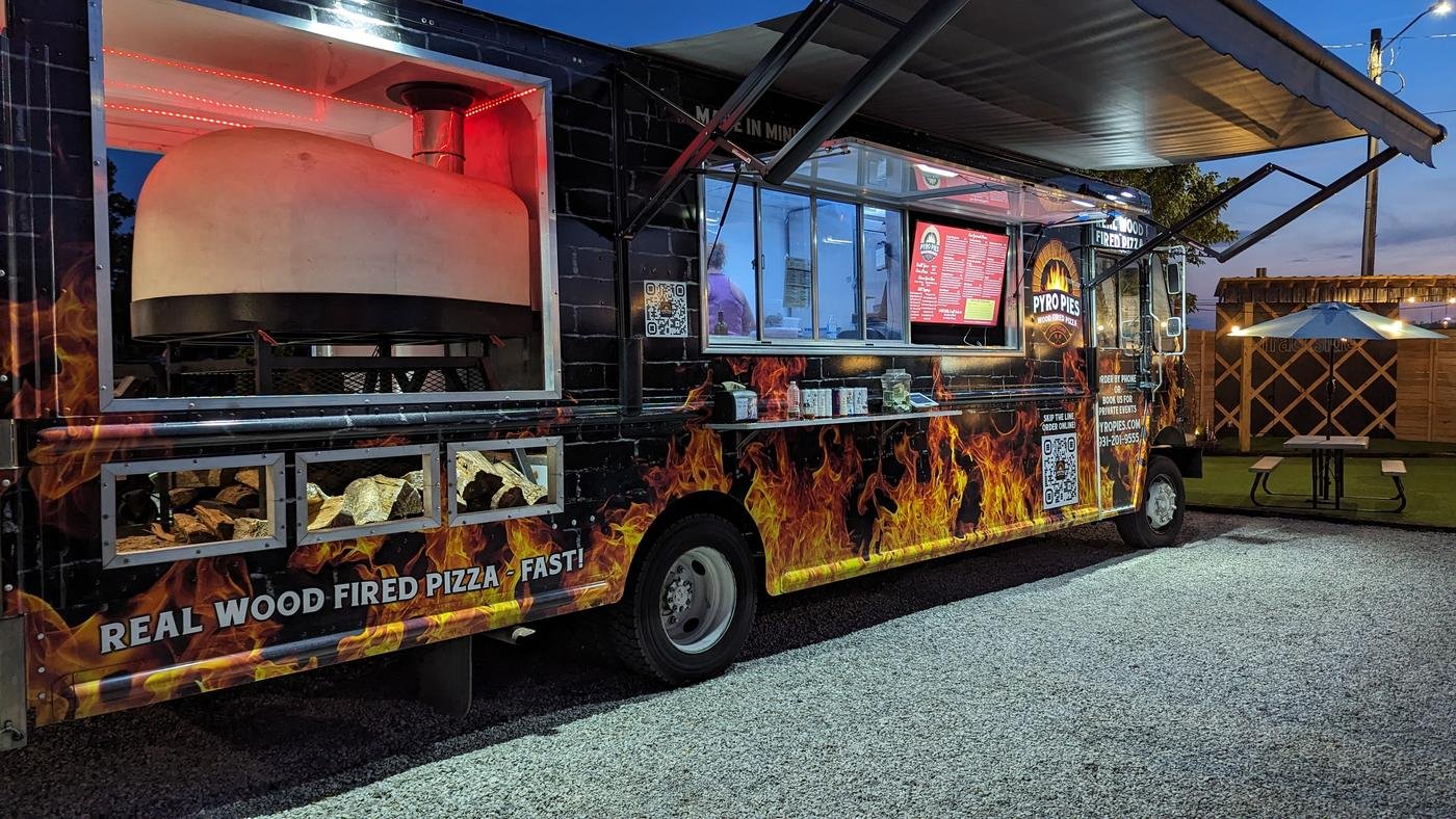 The Pyro Pies truck at dusk with the oven lit and the awning out