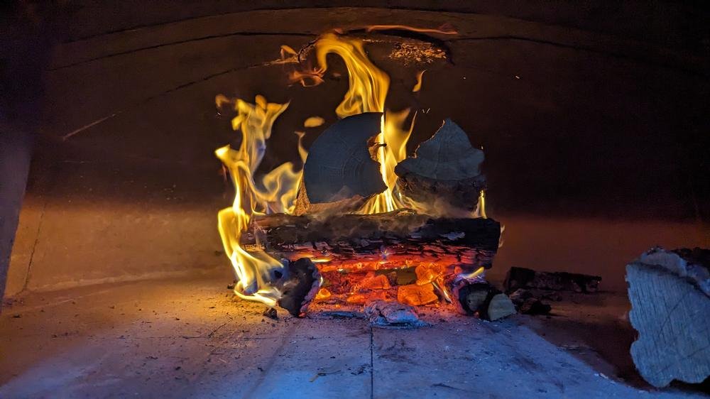 A single log burning on the floor of the wood-fired oven